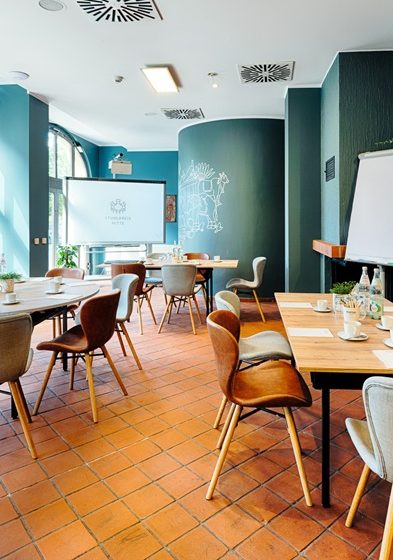 Stuhlkreis Mitte © Andreas Rehkopp Heller Veranstaltungsraum mit drei Tischen in Blockbestuhlung und Whiteboard